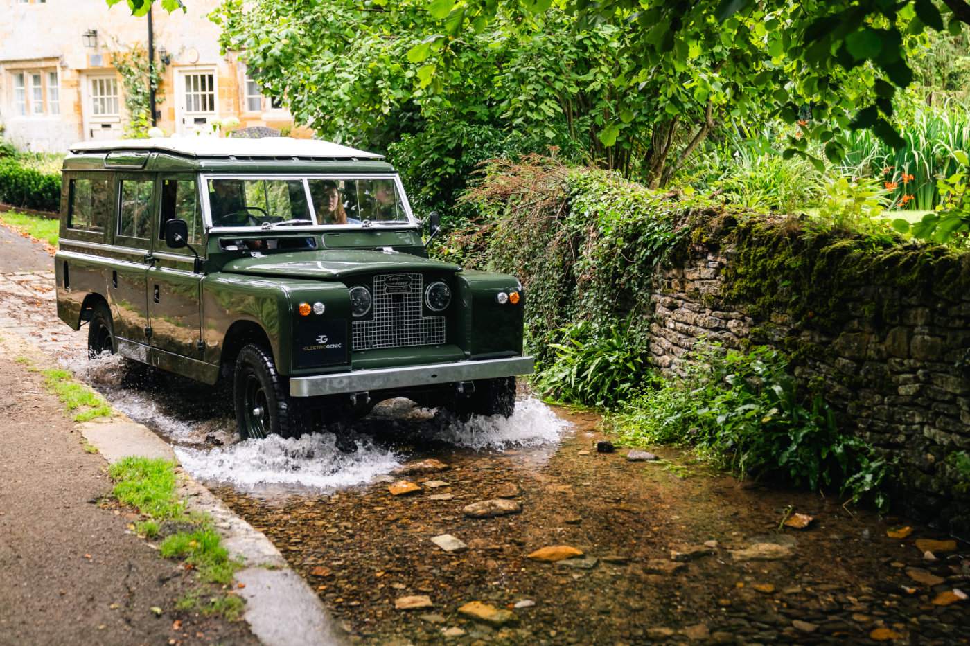 Electrogenic electric Land Rover Series II driving through a Cotswolds ford